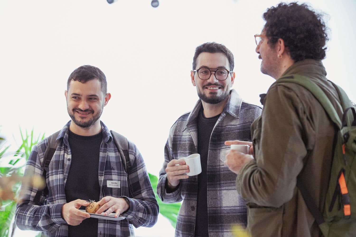 Three attendees talking over coffee between sessions.